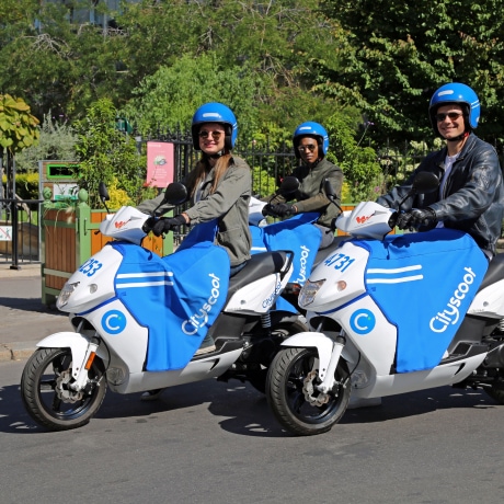 Une illustration de 3 personnes conduisant des scooters Cityscoot.