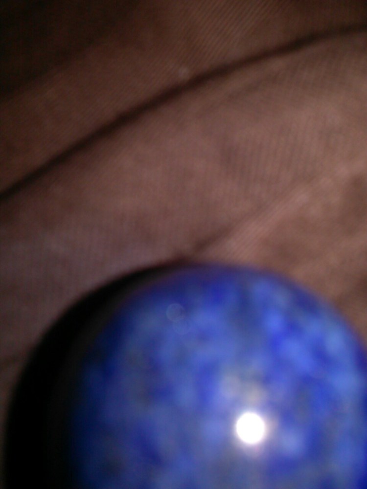 Part of a blue lapis lazuli ball on a brown background, slightly out of focus.