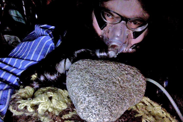 Me in bed with my bipap mask on and a big hunk of granite on my belly.