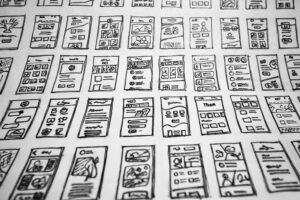 Photograph of a series of illustrations of mobile application screens, possibly mockups for developers. Photograph of a series of illustrations of mobile application screens, possibly mockups for developers.