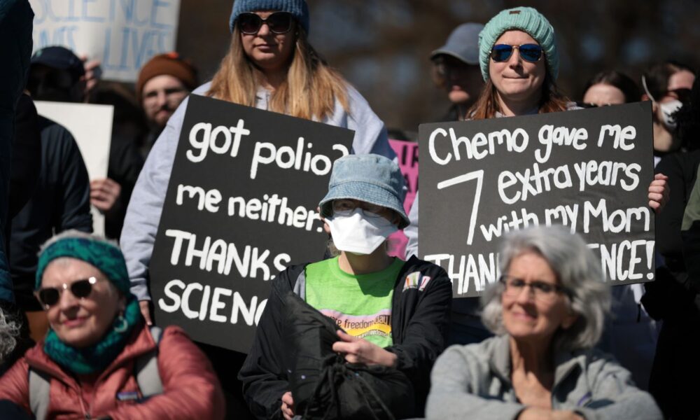 At a rally for science, an attendee holds a sign reading "got polio? me neither. thanks science"