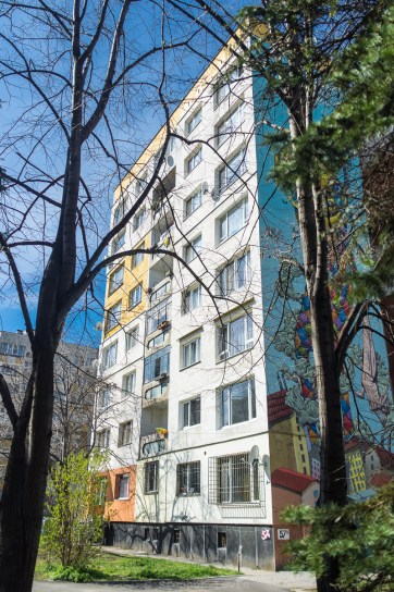 Poduyane quarter, Sofia, Bulgaria, 2016. Fuji X100 w/ +1.4 lens adaptor. The uncoordinated color schemes of privately insulated apartments on the facade lends an accidental Mondriaan-like counterpoint to the neo-psychedelica of the mural on the lateral face of the building.