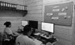 Fotografia de dois trabalhadores realizando atividades administrativas.