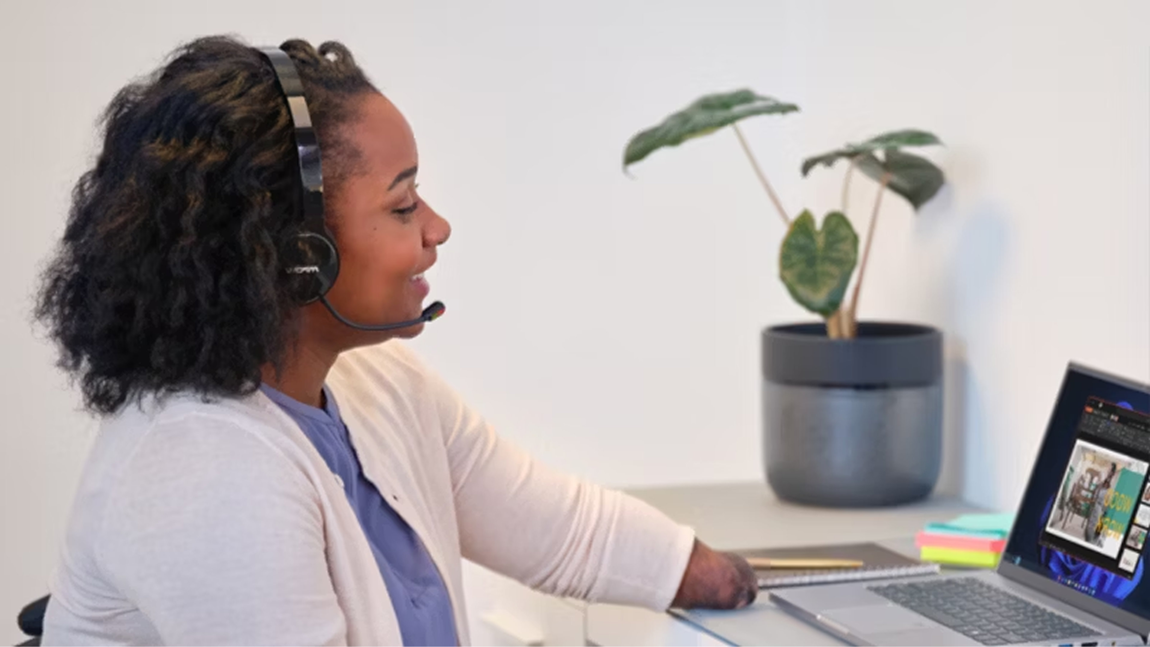 A person wearing a headset working on a laptop at a desk