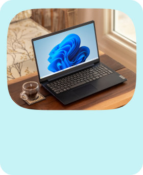 A Windows laptop with the blue bloom screen open on a table with a cup of coffee next to it