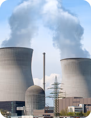 Kernkraftwerk mit zwei großen Kühltürmen, die Dampf gegen den blauen Himmel ausstoßen.