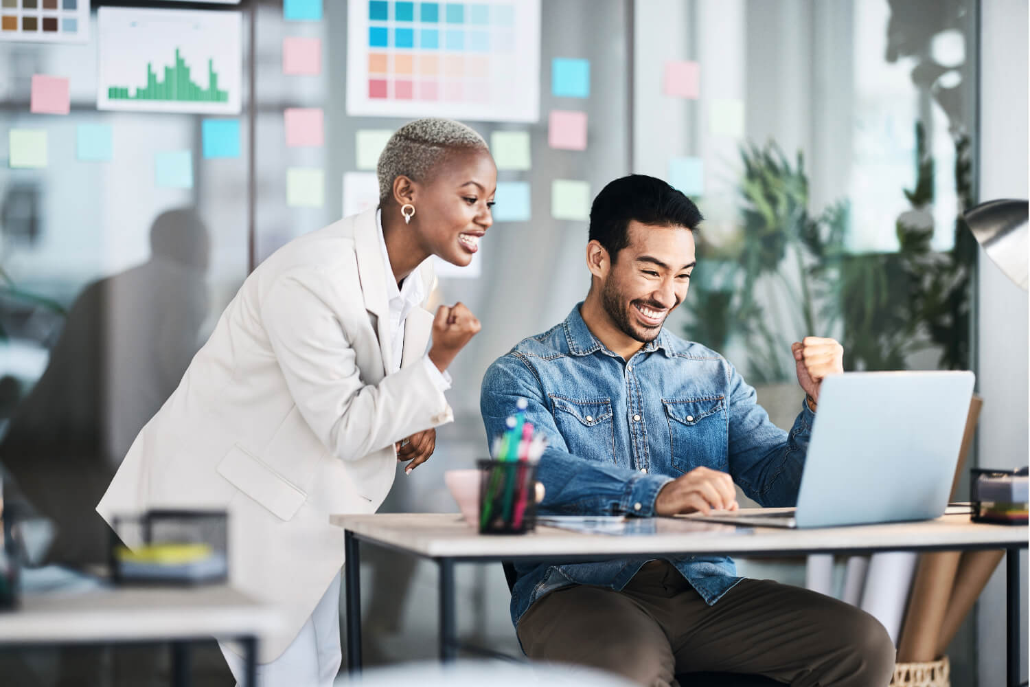 Two colleagues celebrate at a laptop.