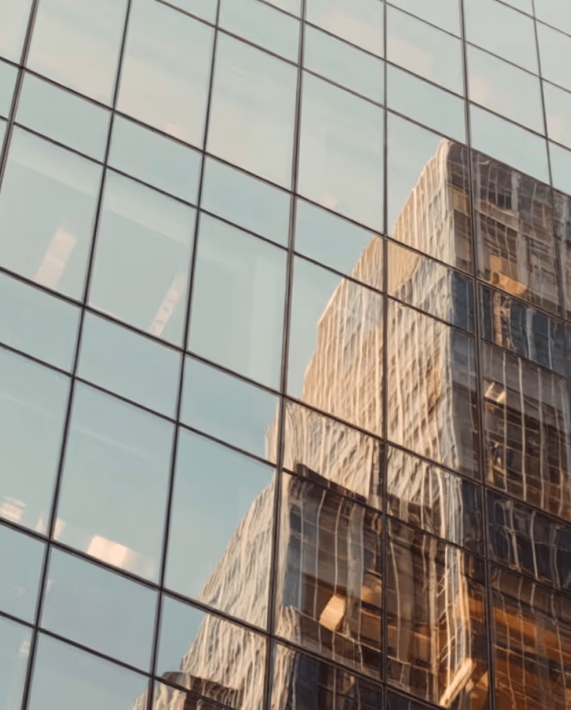 Reflection of a tall building with many windows on the glass facade of another modern skyscraper.