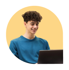 Smiling young man in blue shirt looking at a laptop against a pale yellow background.