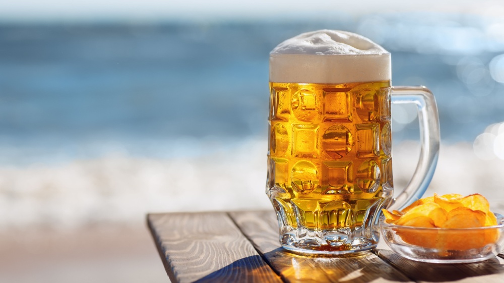 Cold pint of beer on a summery background.