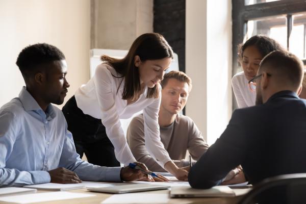Diverse colleagues working on project together, sitting at table in boardroom, working with legal documents, financial report with statistics, employees engaged in teamwork at corporate meeting