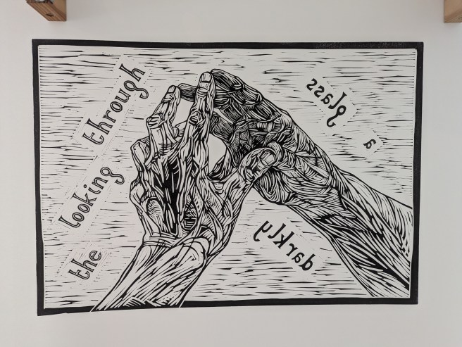 Linoprint of a left hand and its mirror image with text: 'the looking through a glass darkly'