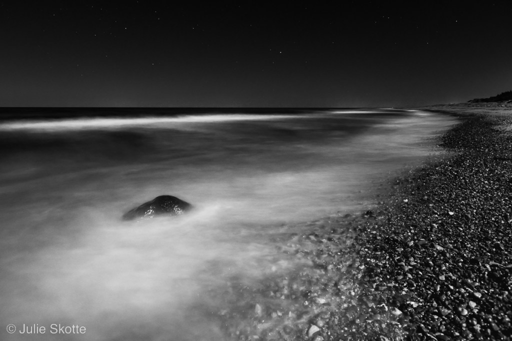Moonlight beach and long shutter of waves crashing the shore, black and white version.