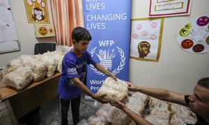 Um menino recebe pão do PMA num abrigo em Gaza