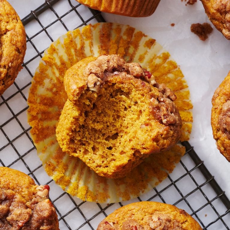 pumpkin streusel muffin with a bite taken out on a wire rack surrounded by other homemade pumpkin muffins