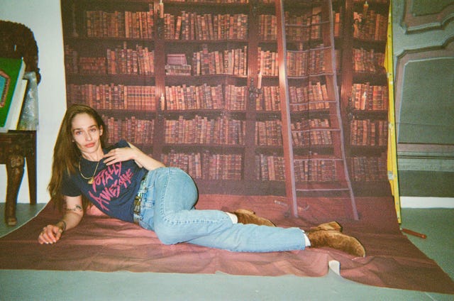 a person lies on a fabric surface in front of a wall featuring a library backdrop a person lies on a fabric surface in front of a wall featuring a library backdrop