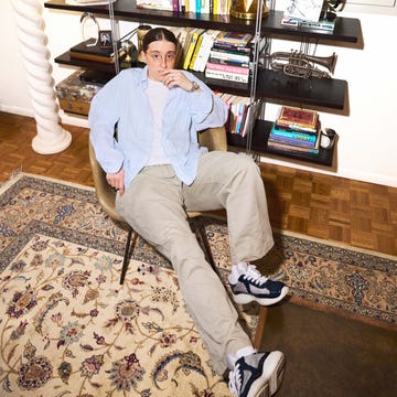 Person relaxing in a chair near a bookshelf and a lamp. Person relaxing in a chair near a bookshelf and a lamp.