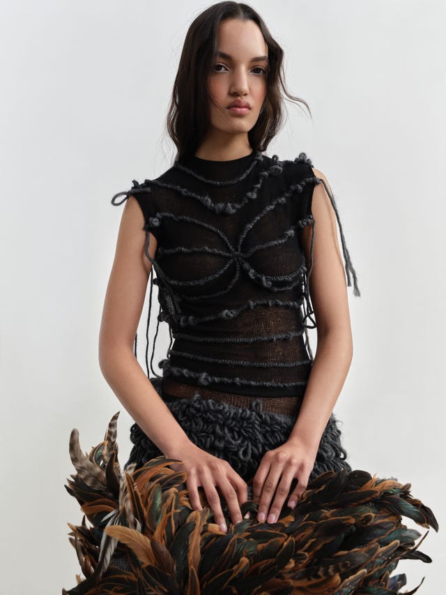 Fashion model wearing an artistic garment with feathered elements. Fashion model wearing an artistic garment with feathered elements.