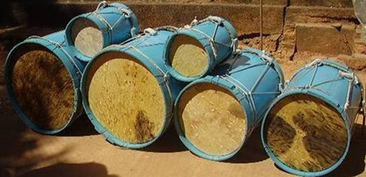 Photograph of six blue and beige drums stacked on top of each other. Photograph of six blue and beige drums stacked on top of each other.