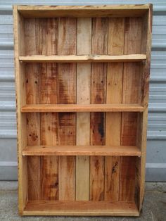 a wooden book shelf sitting on the side of a building next to a garage door