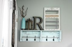 a white shelf with hooks and letters on it in a room next to a window