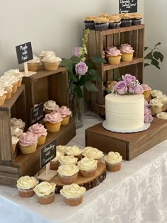 a table topped with lots of cupcakes next to wooden crates filled with cakes