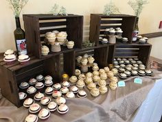 several wooden crates filled with cupcakes on top of a table next to a bottle of wine