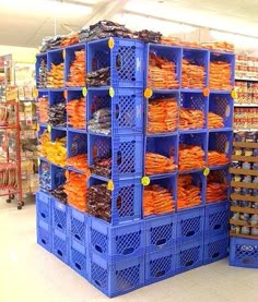 a large stack of blue crates filled with orange items in a grocery store's produce section