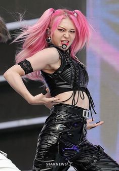 a woman with pink hair and piercings on her chest is performing at a concert