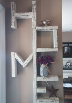 a shelf made out of wooden blocks with flowers in a vase sitting on top of it
