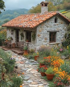 a small stone house surrounded by flowers and greenery