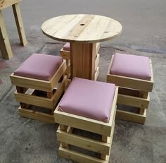 a wooden table and chairs made out of pallet wood with pink cushions on them