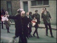Father Daly waves a bloodstained handkerchief as he tries to lead one of the victims of Bloody Sunday, Jackie Duddy, to safety