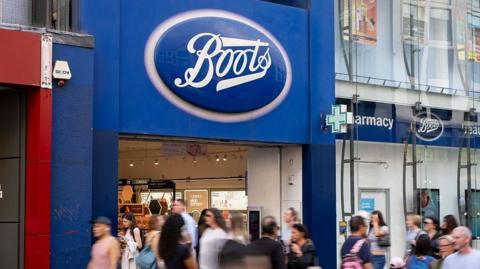 Shoppers walk by a Boots store in central London