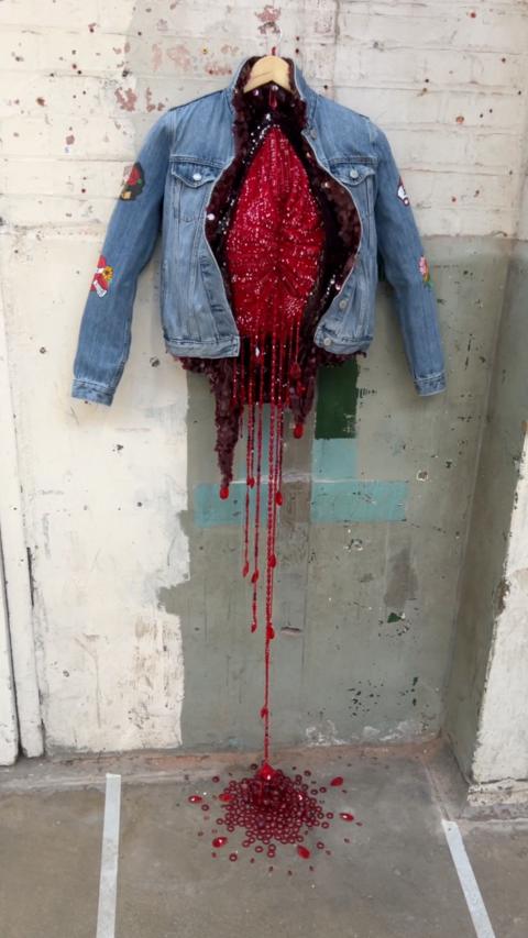 A denim coat with red beads spililng out from it.