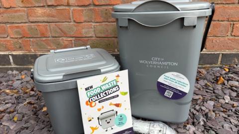 Close up of two grey food wast bins on gravel outside