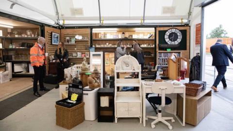 A shop with items for sale including small pieces of furniture in the foreground