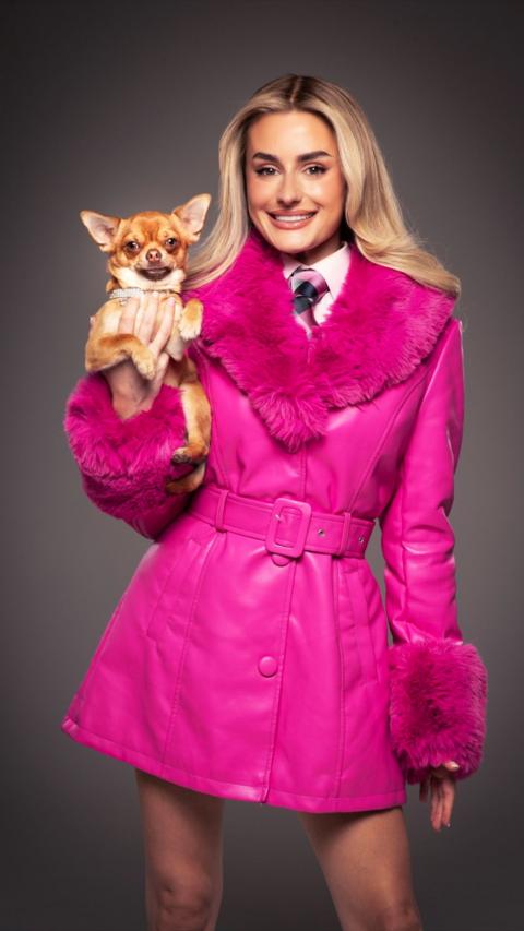 Amber Davies wearing a pink cloak and holding a small dog
