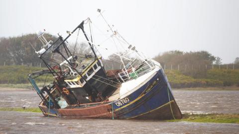 A fishing boat is stranded at Irvine Harbour in Ayrshire after coming loose from its moorings when Storm Boelo passed through the area.