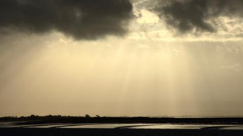 Crepuscular rays shining through cloud above the coast