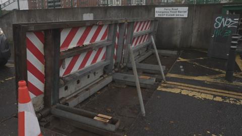 A flood defence barrier, with a chequed red and white pattern on it.