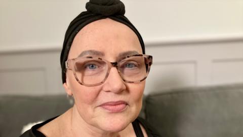 A woman with a black hairband and glasses.