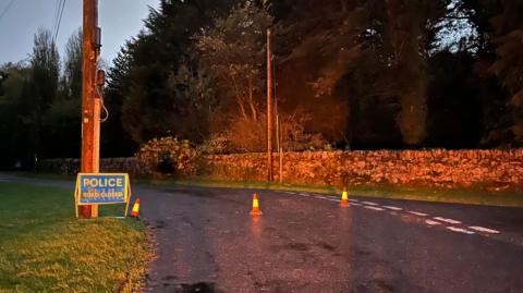 Police road closed sign sign and cones on a country road at night