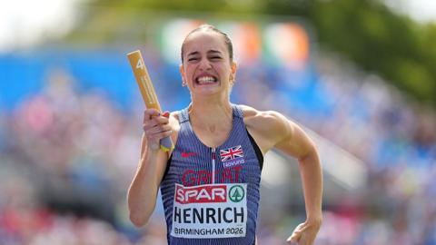 Charlotte Henrich in Great Britain vest grimaces as she runs with the baton in a women's 4x400m relay