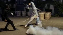 Một người biểu tình ném trả một quả lựu đạn hơi cay về phía lực lượng cảnh sát trong cuộc biểu tình chống chính phủ do sinh viên tổ chức tại Tirana, Albania, ngày 19/10
