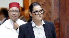 Fatima El Mansouri, vestida con camisa y un saco azul y el cabello recogido, ingresa al parlamento de Marruecos