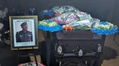 Ifoto ya Sergeant Robert Kabera yari yashizwe iruhande y’isandugu yiwe igihe c’amaziko yabaye ku wa 21 Gitugutu(10) 2026, i Kammengo muri Uganda.