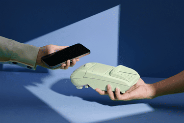 A hand holding a smartphone and a hand holding a payment terminal