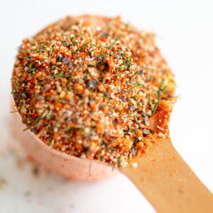 A spoon full of the best steak seasoning on a white surface.