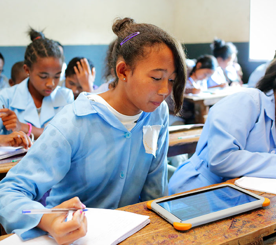 Girl in school classroom in Africa working off a tablet.